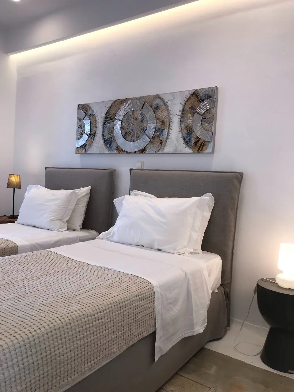 A bedroom with two beds, white bedding, and abstract wall art.