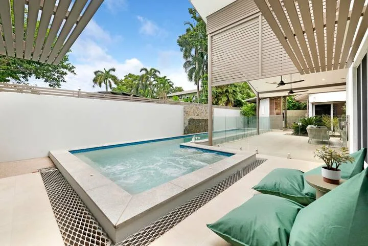 A small outdoor pool sits beside a patio with cushioned seating.