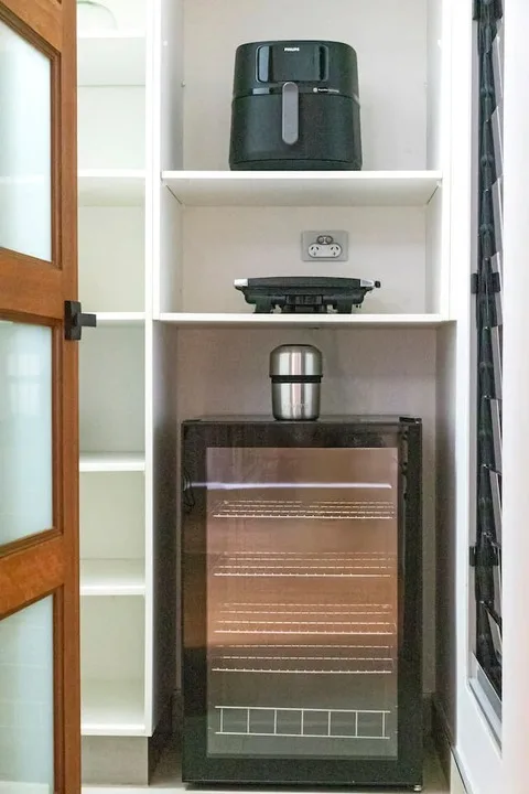 Un rincón de cocina con un horno de sobremesa y pequeños electrodomésticos en estantes abiertos.