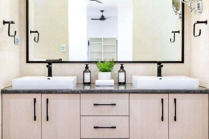 Un tocador de baño con dos lavabos se encuentra bajo un espejo amplio.
