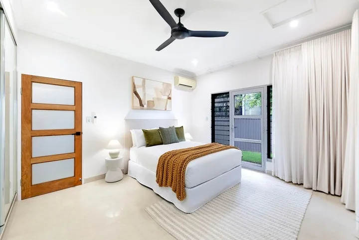 Un dormitorio luminoso con una cama bien arreglada y cortinas de suelo a techo.