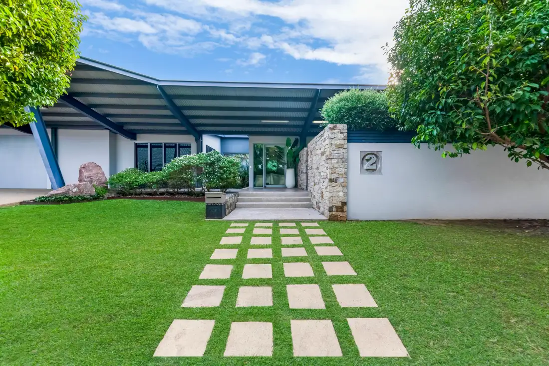 Un camino de losas cruza un césped verde y conduce a la entrada de un edificio moderno.