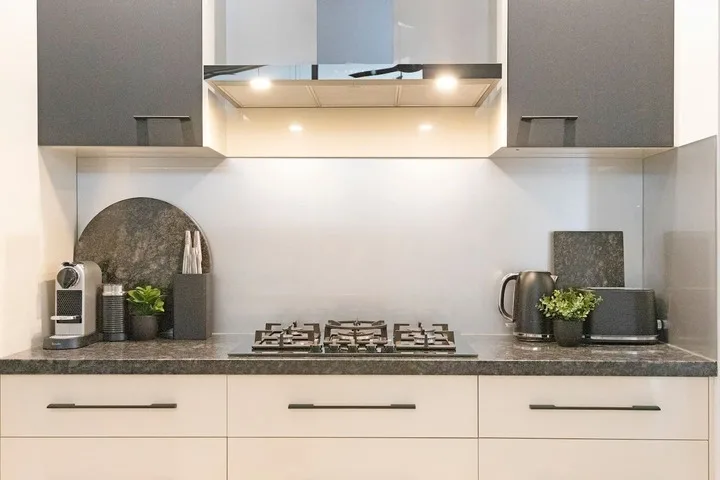 Una cocina moderna con una placa de cocción bajo una campana iluminada.