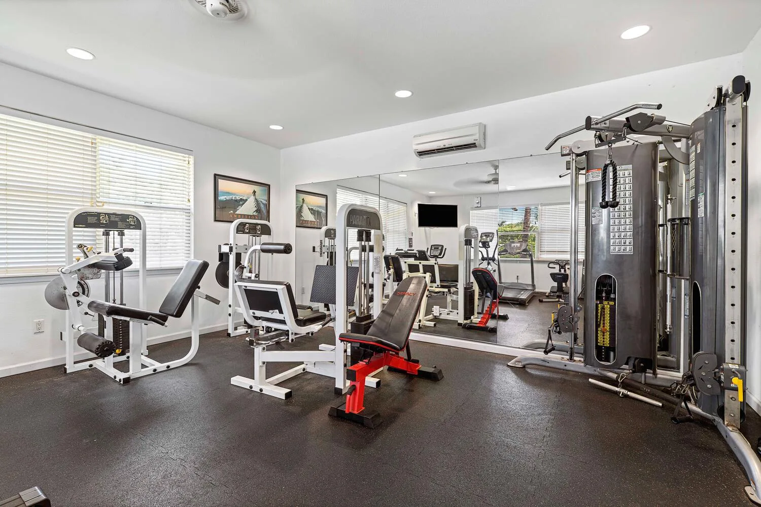 Un gimnasio con máquinas de ejercicio y equipo de entrenamiento con pesas.