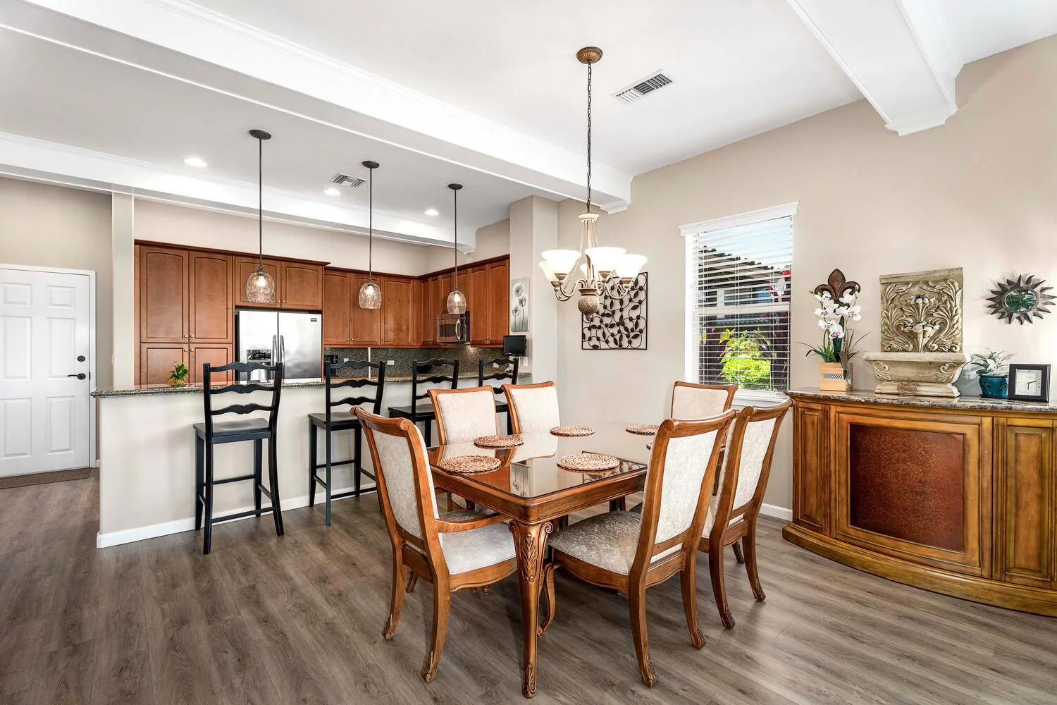 Comedor con mesa y sillas de madera junto a una cocina abierta.