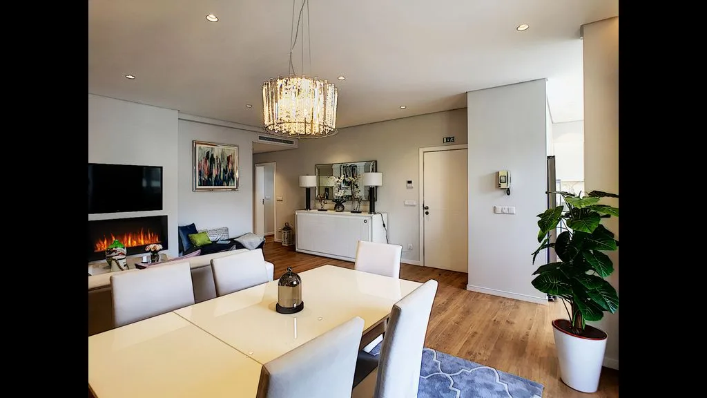 A bright living and dining area with seating, a table, and a television.