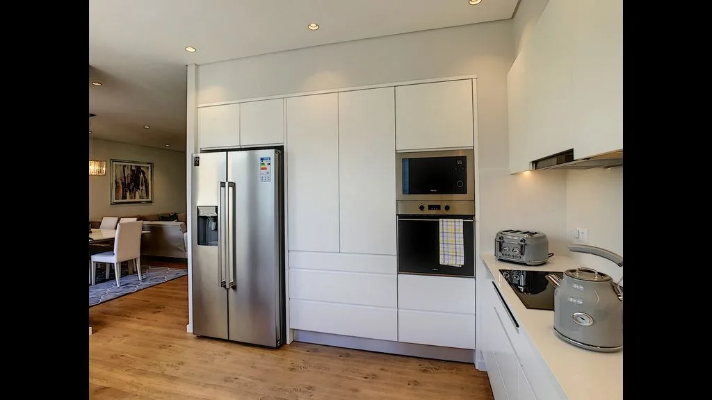 A modern kitchen with white cabinets and stainless steel appliances.
