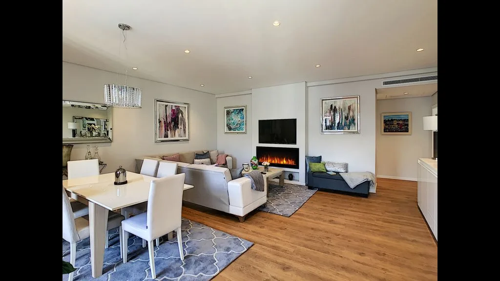 A living room with seating, a dining table, and a fireplace.