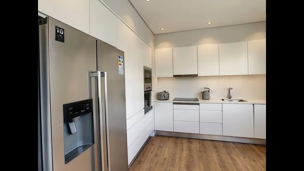 A modern kitchen with white cabinets and stainless steel appliances.
