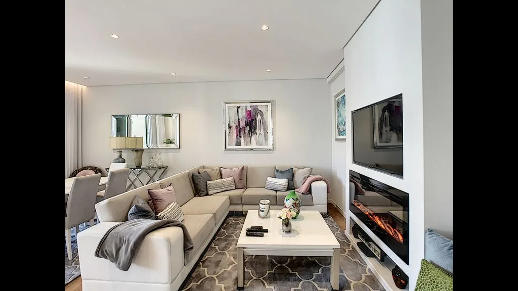 A bright living room with sectional seating and a wall-mounted television.