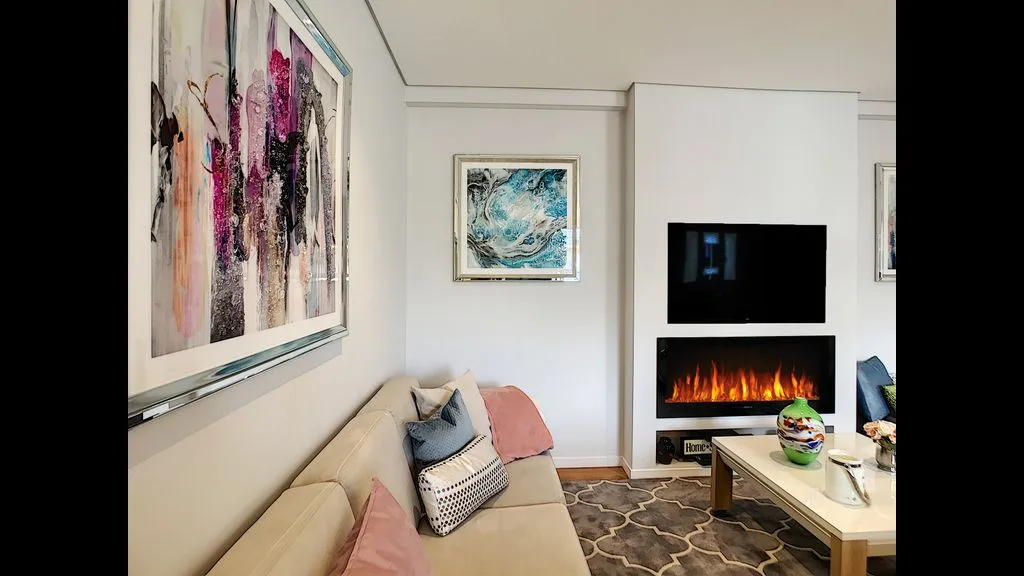 A living room with a beige sofa, wall art, and a fireplace.