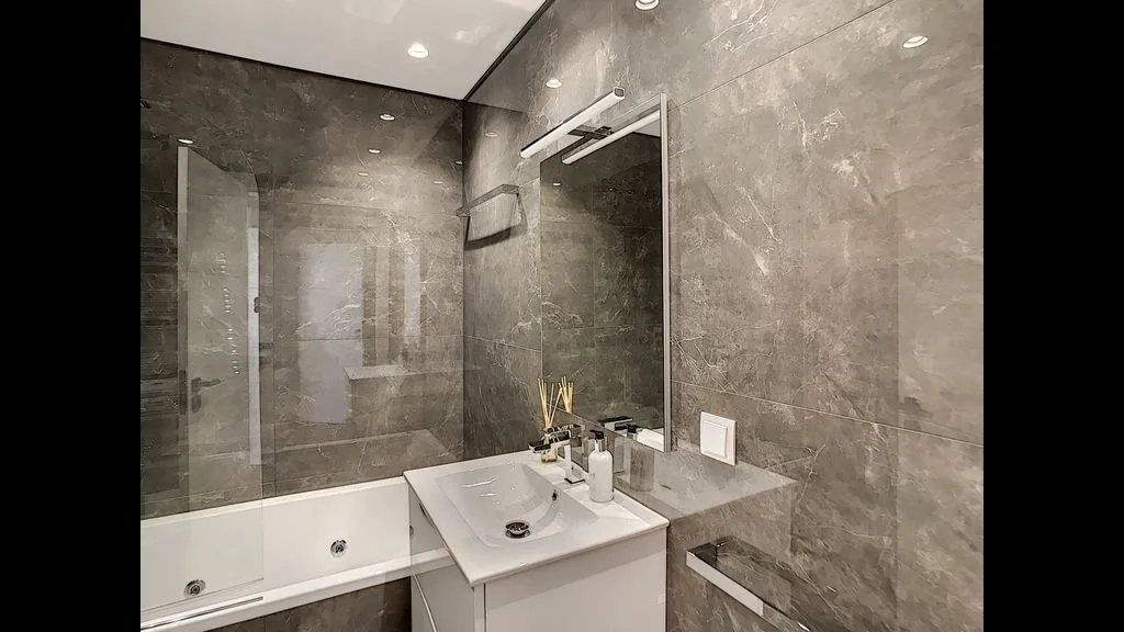 A bathroom with a bathtub, glass shower screen, and sink.