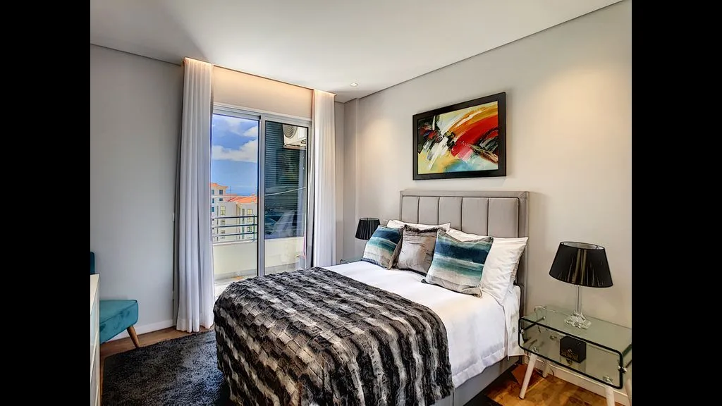 A bedroom with a bed, striped bedding, and a glass door to a balcony.