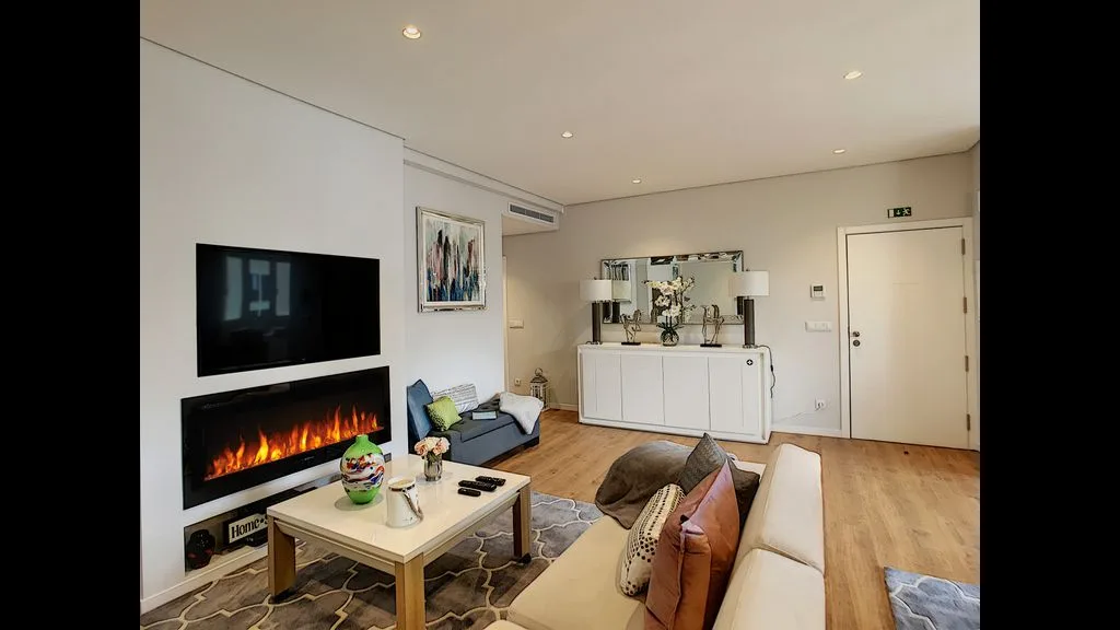 A bright living room with a sofa, coffee table, and wall-mounted television.