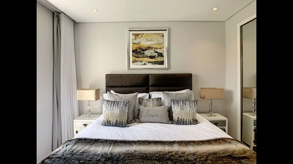 A bedroom with a neatly made bed and framed artwork above the headboard.