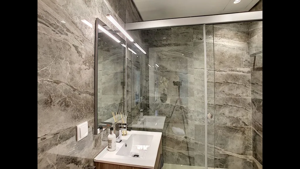 A modern bathroom with a sink and glass shower.