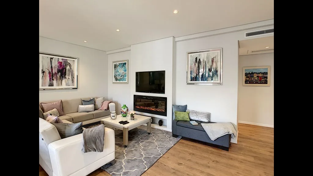 A bright living room with seating arranged around a television and coffee table.