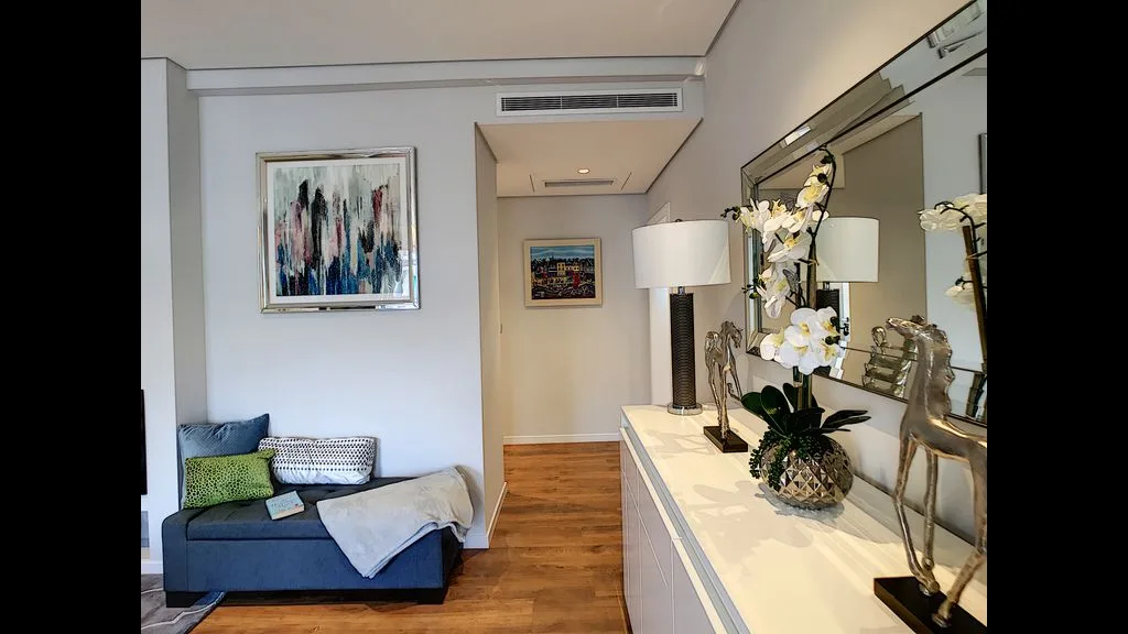 A living room with a small seating area and a long console beneath a mirror.
