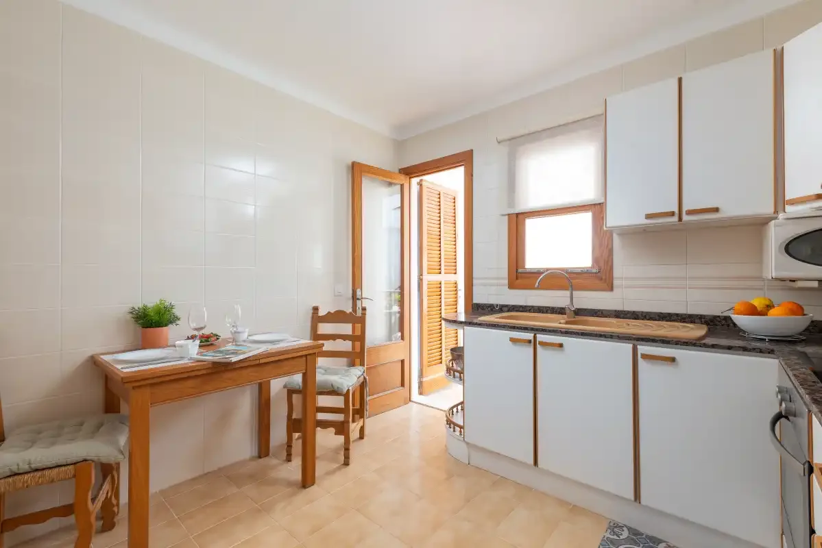A tiled kitchen with a dining table and light-colored cabinets.
