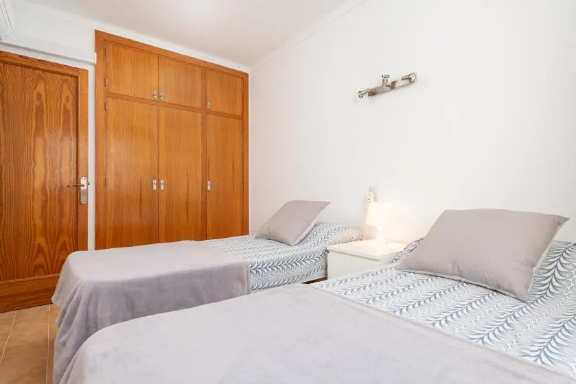 A bedroom with two beds and wooden wardrobes.