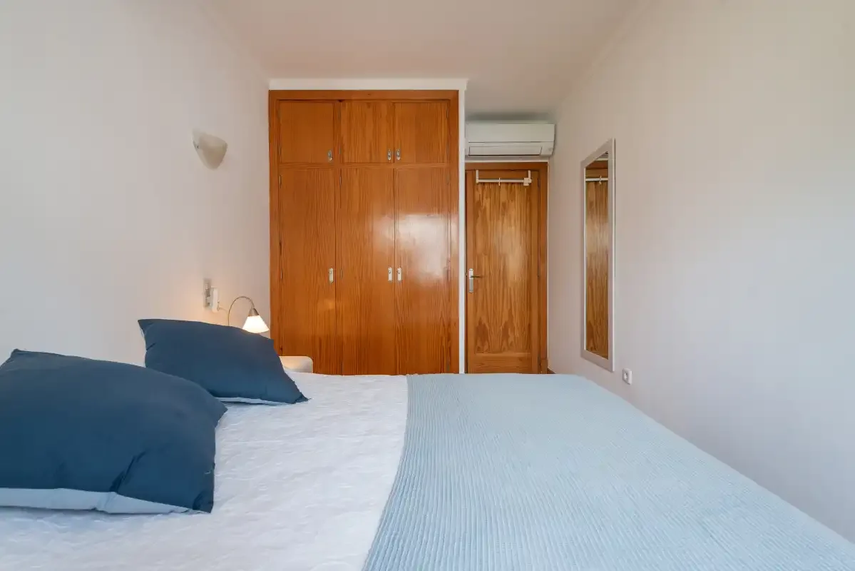 A bedroom with blue bedding and wooden wardrobes.