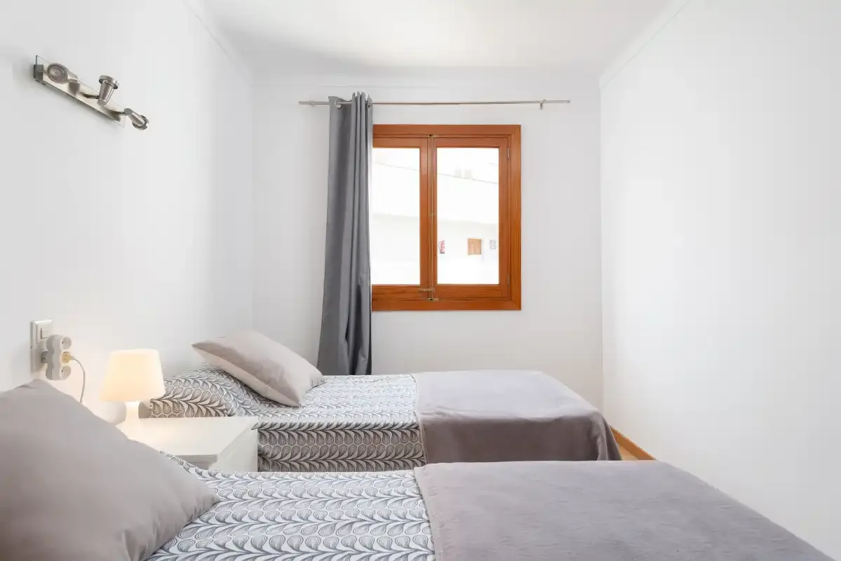 A bedroom with two beds beside a window.