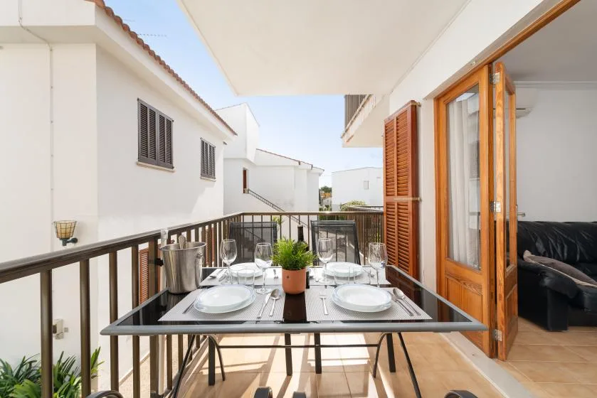 A small outdoor dining area sits on a balcony beside an open wooden door.