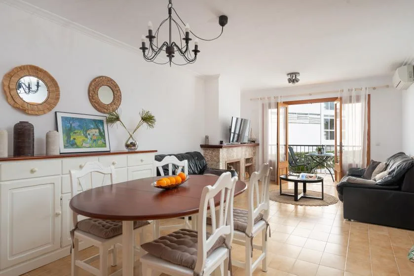 A bright living and dining room with a table, seating, and a balcony door.