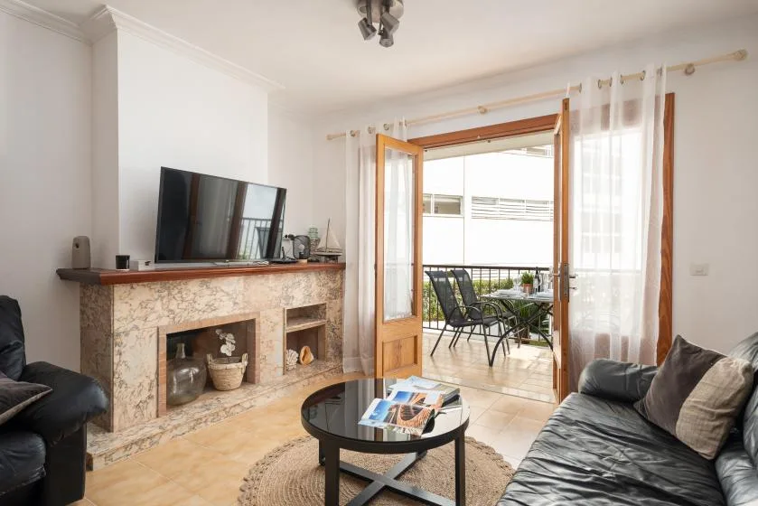 A living room with seating around a coffee table and open doors to a balcony.
