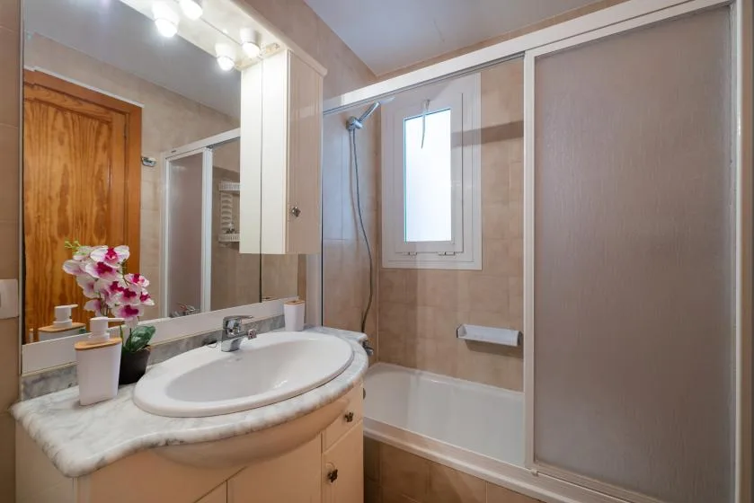 A bathroom with a sink, mirror, bathtub, and shower.