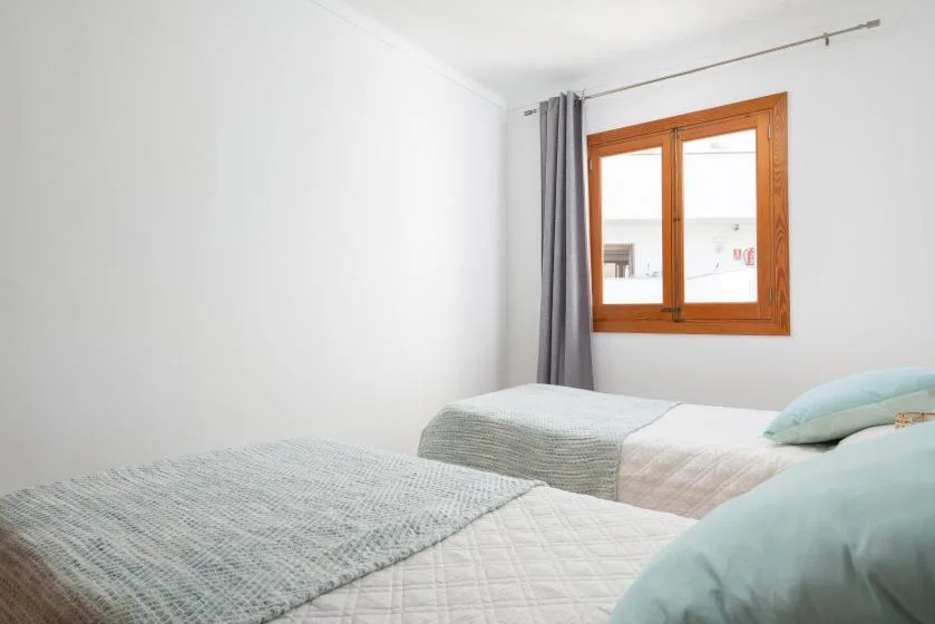A bedroom with beds beside a wooden-framed window.