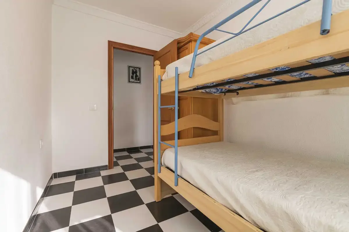 A bedroom with wooden bunk beds and a black-and-white checkered floor.