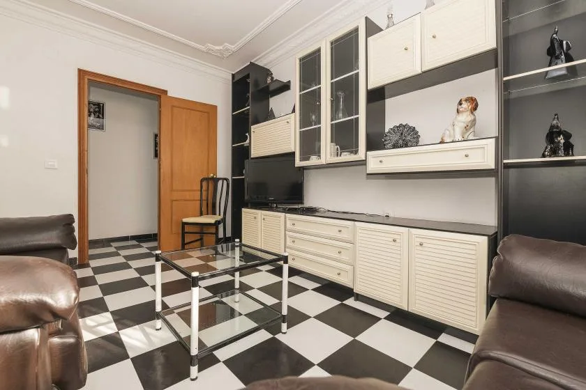 A living room with a black-and-white checkered floor and built-in cabinetry.