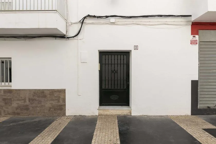 A street-facing building entrance with a dark barred door and pale walls.