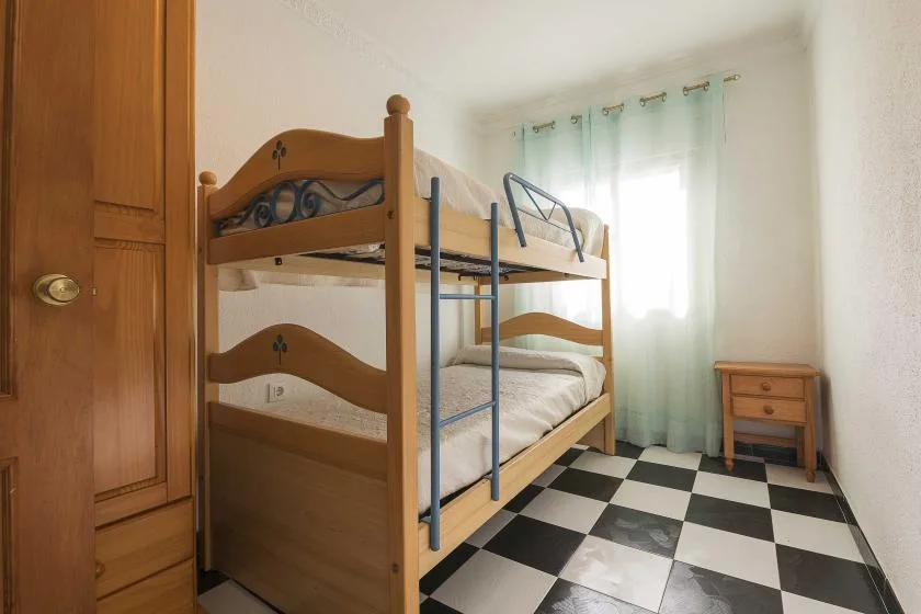 A bedroom with wooden bunk beds and a black-and-white tiled floor.