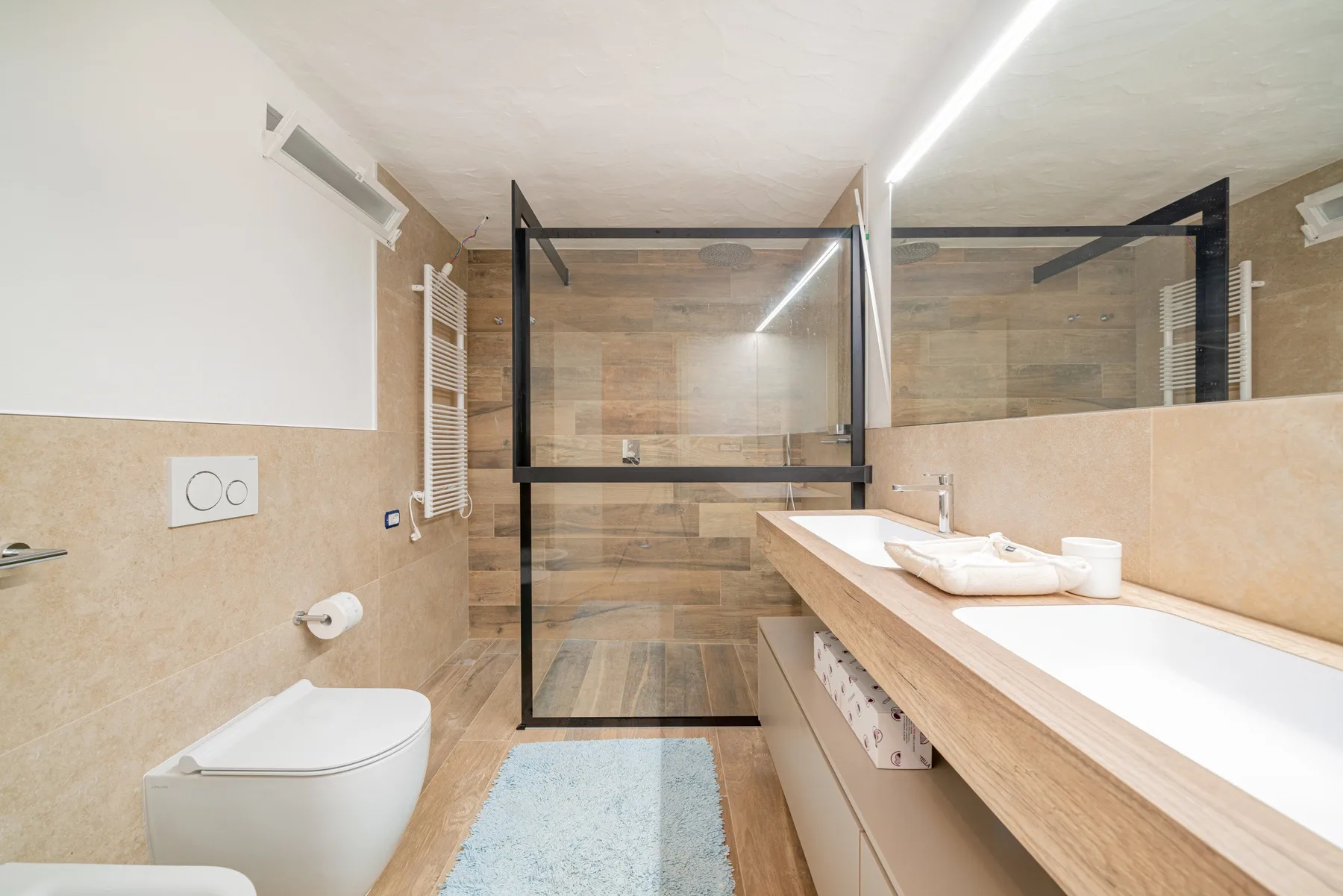 A modern bathroom with a glass shower and a long vanity.