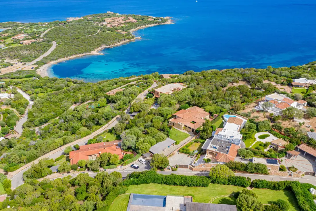 Aerial view of homes among green vegetation beside a blue bay.