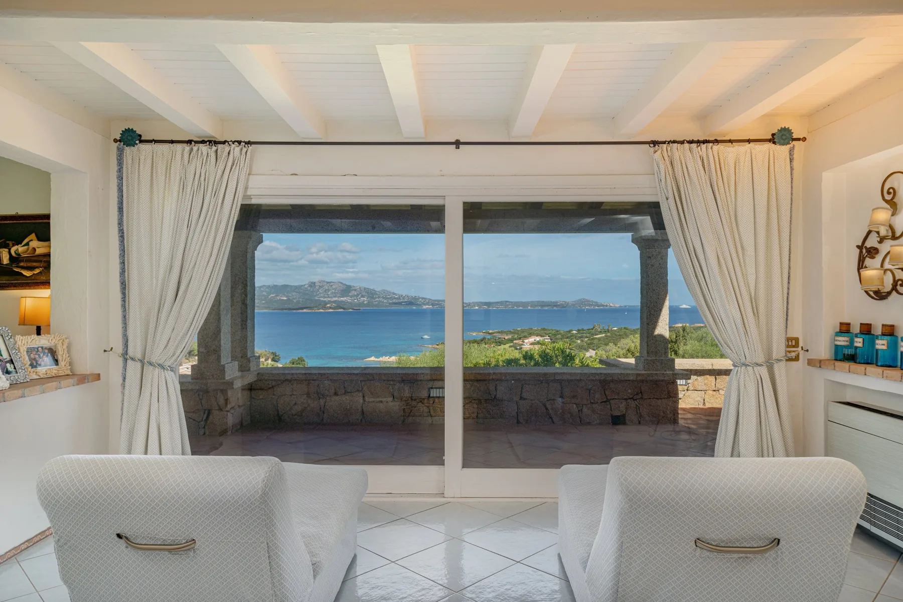 A bright sitting area opens onto a terrace with a view of the sea.