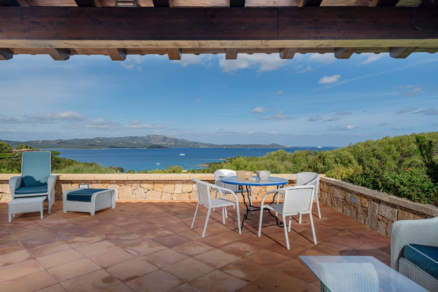 A tiled terrace has outdoor seating and a table overlooking the sea.