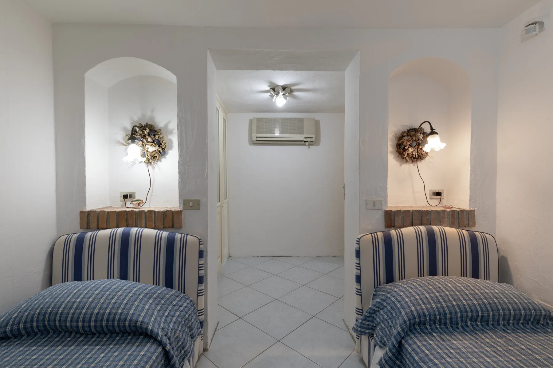 A bedroom with two single beds and a tiled floor.