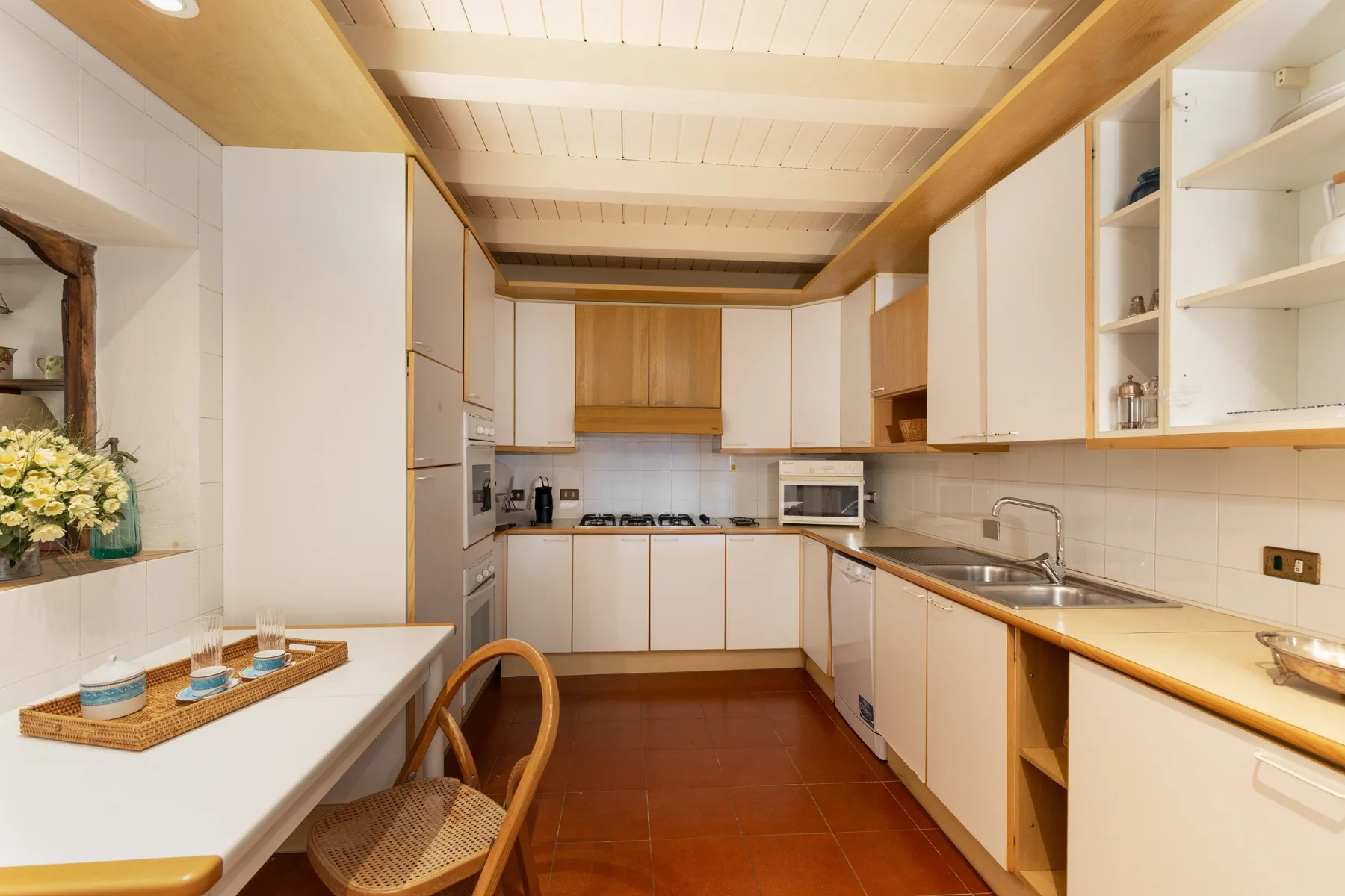 A bright kitchen with white cabinets and a long countertop.
