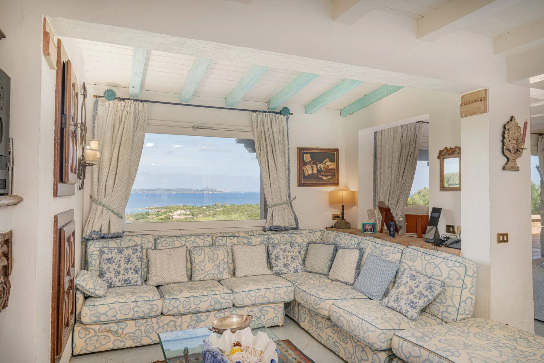 A living room with patterned seating and a wide window overlooking the water.