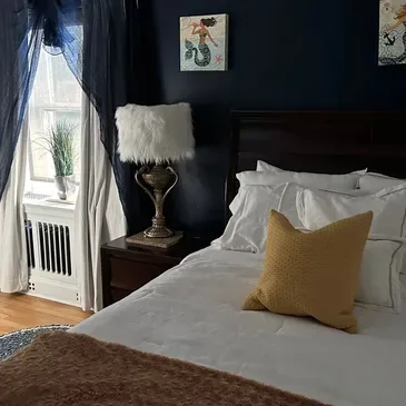 Dormitorio acogedor con paredes oscuras y ropa de cama mullida.