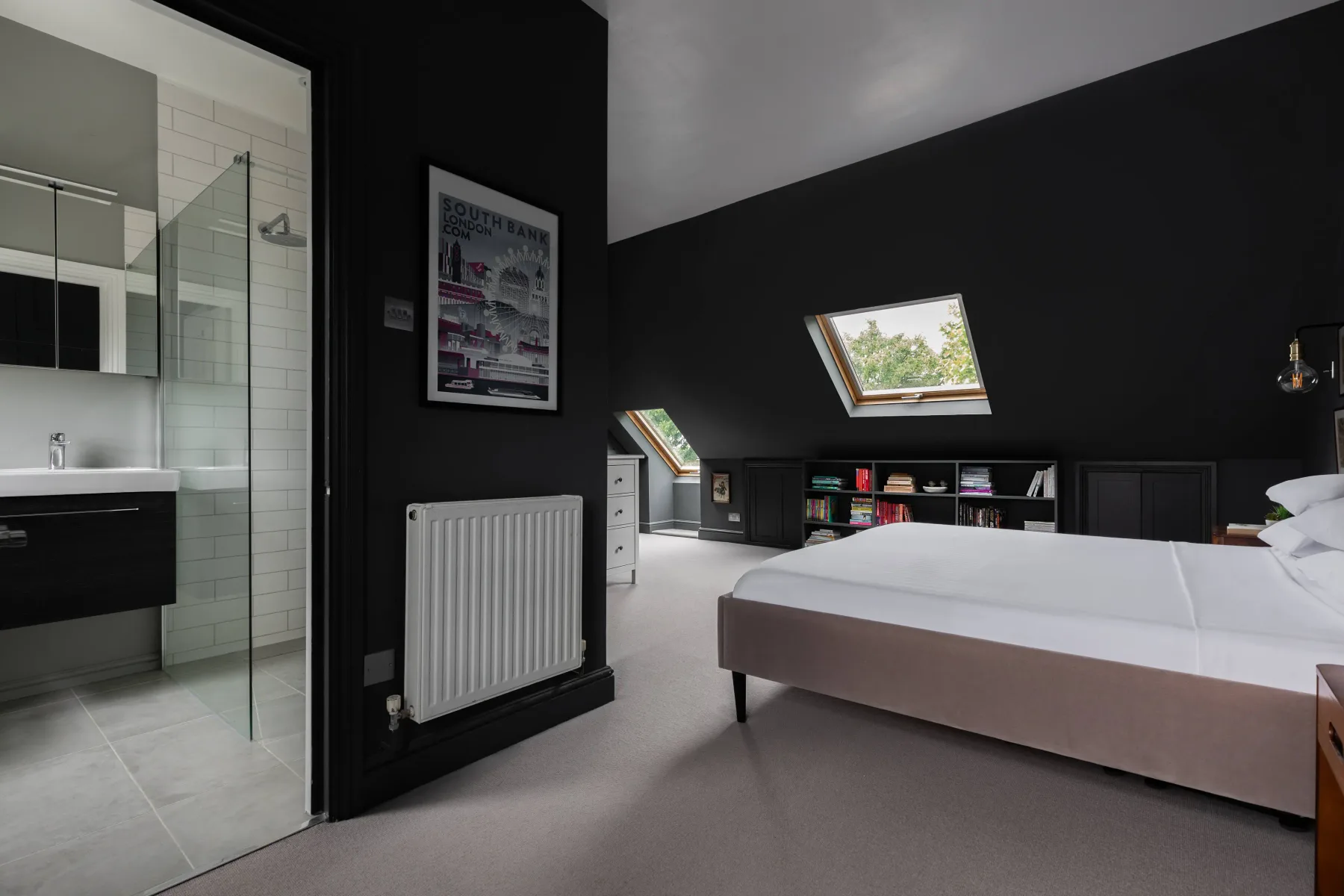 A bedroom with a low bed, skylights, and an adjoining bathroom.