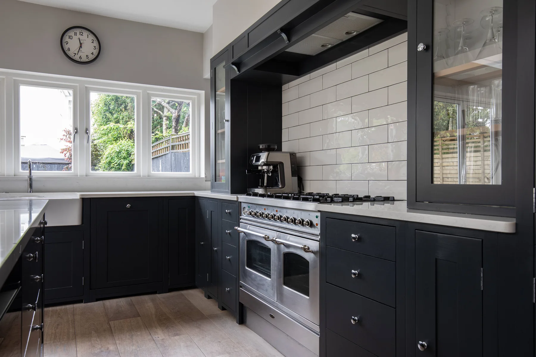 A dark-cabinet kitchen with a stainless steel range and windows above the counter.