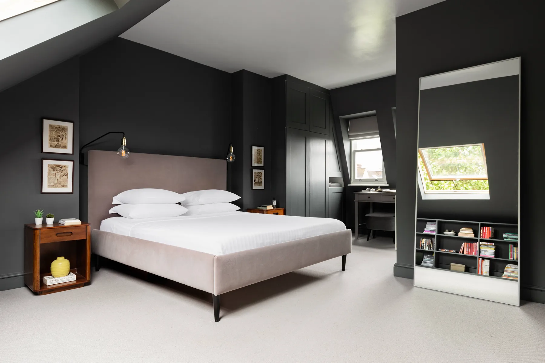 A bedroom with a neatly made bed and dark walls.