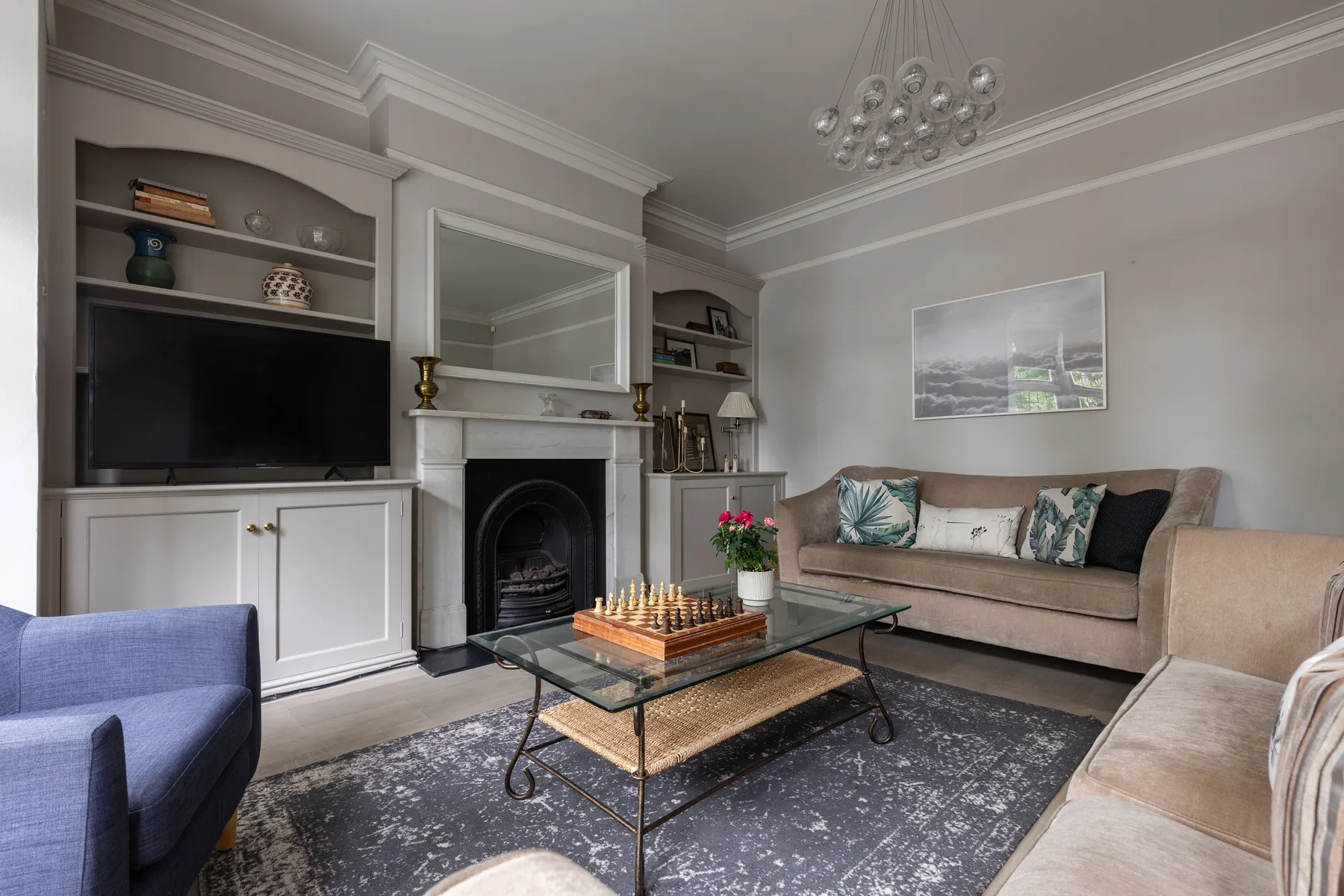 A living room with seating around a glass coffee table and fireplace.