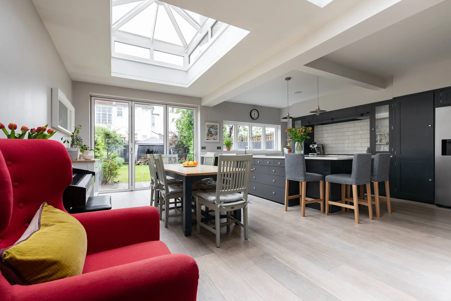 An open-plan kitchen and dining area with a table beneath a large skylight.