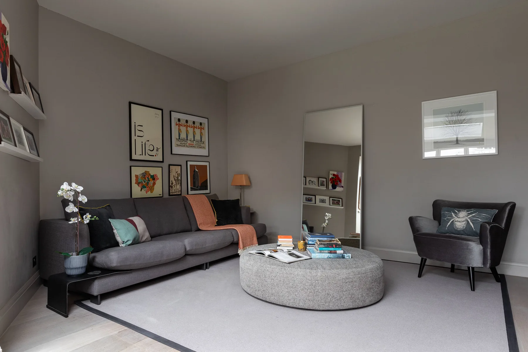A living room with a gray sofa, an armchair, and a round ottoman.