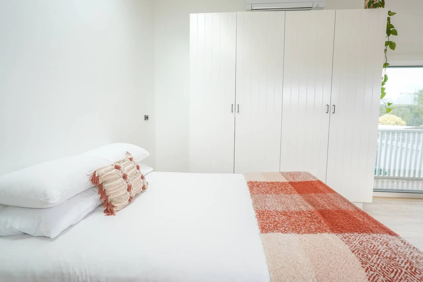A bright bedroom with white bedding and a large wardrobe.